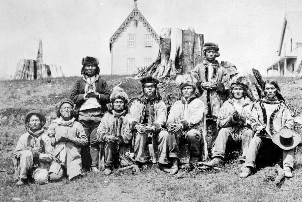 Nine of the greatest Indian Chiefs of British Columbia dressed in their fur caps, buckskin coats & moccasins.